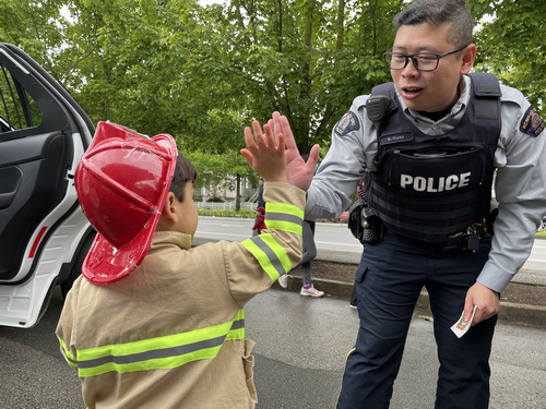 RCMP officer hi-fives a young child dressed as a fireman. 