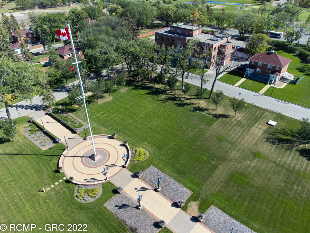 Image of Depot, the RCMP's training facility grounds, with a large flag pole in the middle, surrounded by grass and various buildings.